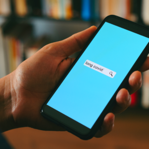 Ein Mann sucht mithilfe seines Smartphone nach einer Selbsthilfegruppe für Long-Covid oder Post-Covid Betroffene