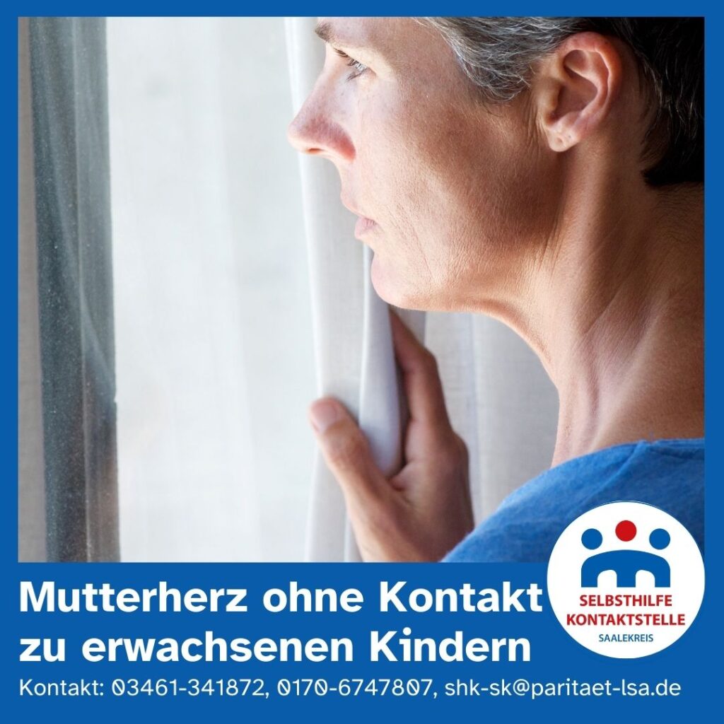 Eine Frau mittleren Alters mit grauen Haaren blickt traurig und sehnsüchtig zugleich aus dem Fenster.