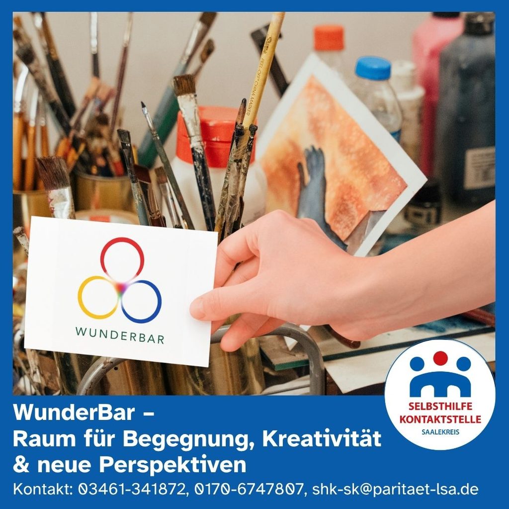 Eine weibliche Hand hält eine Karte ins Bild auf der das Logo der Wunderbar abgebildet ist. Dahinter sieht man jede Menge Utensilien für kreative Beschäftigung.